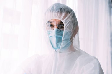 Erkek doktor ya da bilim adamı koruyucu giysi ve yüz maskesi giyiyor. 