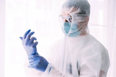 Erkek doktor ya da bilim adamı koruyucu giysi ve yüz maskesi giyiyor. 