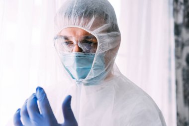 Erkek doktor ya da bilim adamı koruyucu giysi ve yüz maskesi giyiyor. 