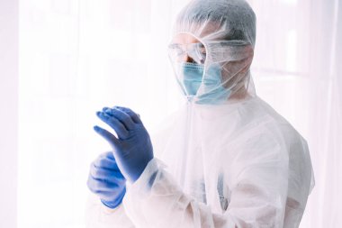 Erkek doktor ya da bilim adamı koruyucu giysi ve yüz maskesi giyiyor. 