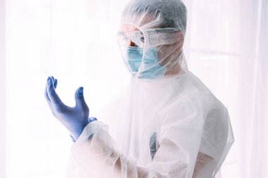Erkek doktor ya da bilim adamı koruyucu giysi ve yüz maskesi giyiyor. 