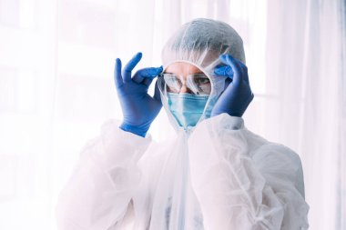 Erkek doktor ya da bilim adamı koruyucu giysi ve yüz maskesi giyiyor. 