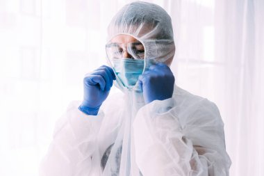 Erkek doktor ya da bilim adamı koruyucu giysi ve yüz maskesi giyiyor. 