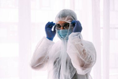 Erkek doktor ya da bilim adamı koruyucu giysi ve yüz maskesi giyiyor. 
