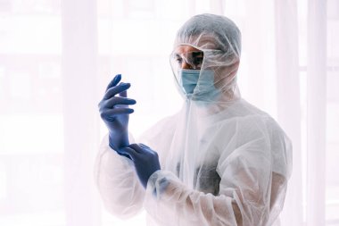 Erkek doktor ya da bilim adamı koruyucu giysi ve yüz maskesi giyiyor. 