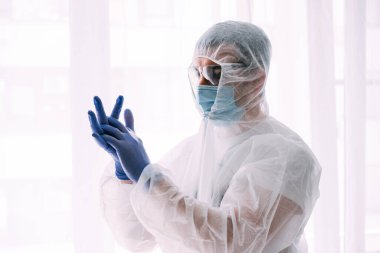 Erkek doktor ya da bilim adamı koruyucu giysi ve yüz maskesi giyiyor. 