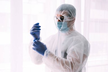 Erkek doktor ya da bilim adamı koruyucu giysi ve yüz maskesi giyiyor. 
