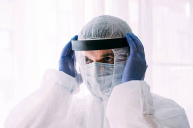 Erkek doktor ya da bilim adamı koruyucu giysi ve yüz maskesi giyiyor. 