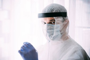 Erkek doktor ya da bilim adamı koruyucu giysi ve yüz maskesi giyiyor. 