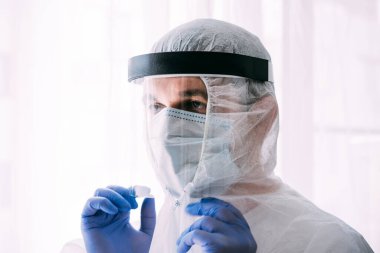 Erkek doktor ya da bilim adamı koruyucu giysi ve yüz maskesi giyiyor. 
