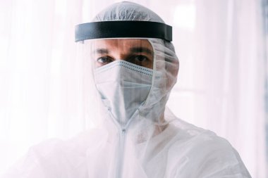 Erkek doktor ya da bilim adamı koruyucu giysi ve yüz maskesi giyiyor. 