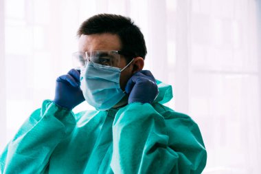 Erkek doktor ya da bilim adamı koruyucu giysi ve yüz maskesi giyiyor. 