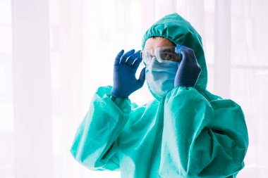 Erkek doktor ya da bilim adamı koruyucu giysi ve yüz maskesi giyiyor. 