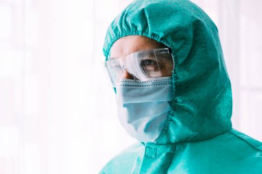 Erkek doktor ya da bilim adamı koruyucu giysi ve yüz maskesi giyiyor. 