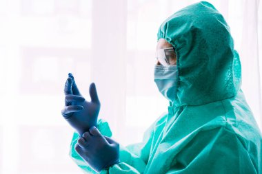 Erkek doktor ya da bilim adamı koruyucu giysi ve yüz maskesi giyiyor. 
