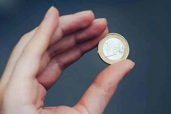 Business woman holding one euro coin between fingers — Stock Photo, Image