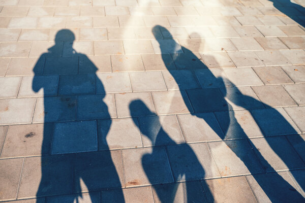 People casting shadows on the pavement