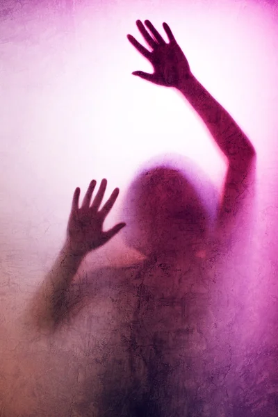 Mulher presa, silhueta de volta iluminada de mãos atrás de vidro fosco — Fotografia de Stock