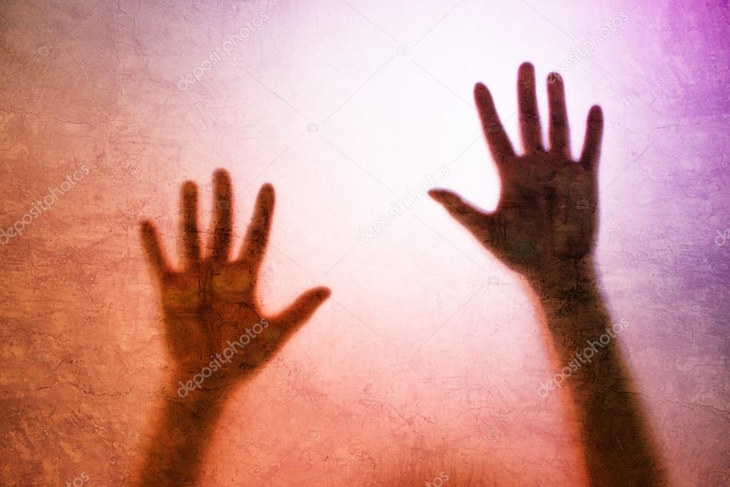 Captured person, back lit silhouette of hands behind matte glass