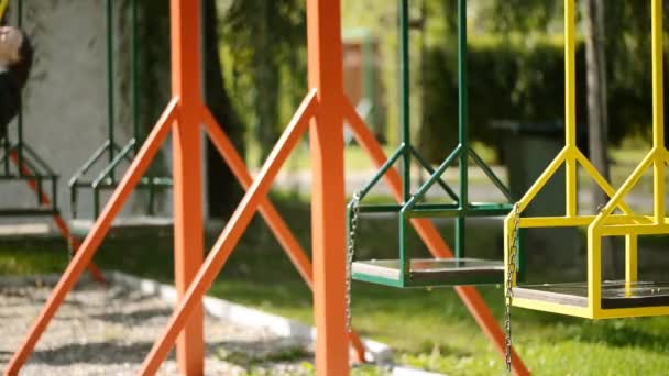 Unrecognizable teenage schoolgirl on swing in park — Stock Video