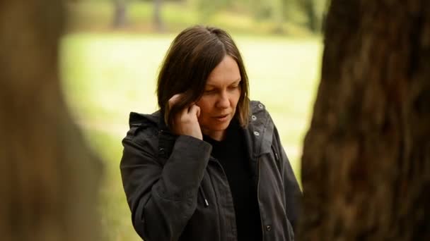Mulher adulta jovem bonita falando no smartphone no parque de outono — Vídeo de Stock