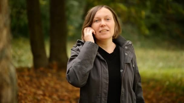Güzel genç yetişkin kadın smartphone cep telefonu ile sonbahar Park söz — Stok video