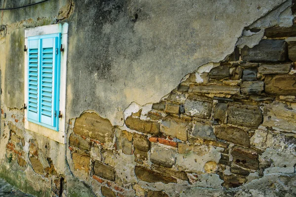 Pared de ladrillo envejecido y vieja ventana azul — Foto de Stock