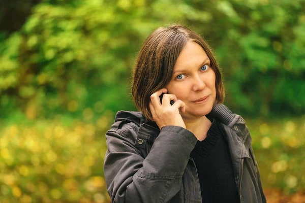 美丽的女人谈移动电话在秋天的公园 — 图库照片