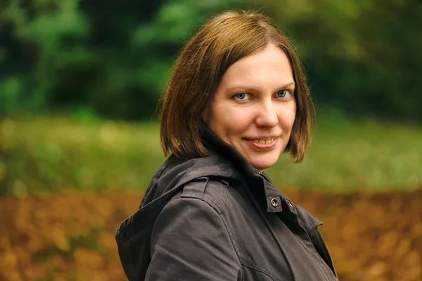 Beautiful smiling young adult woman in autumn park — Stock Photo, Image