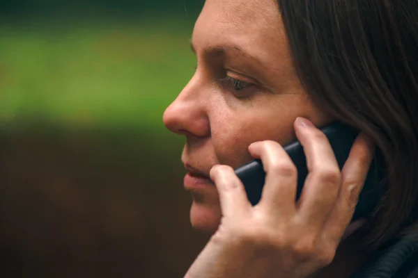 Kvinna med allvarliga ansikte uttryck prata telefon i park — Stockfoto