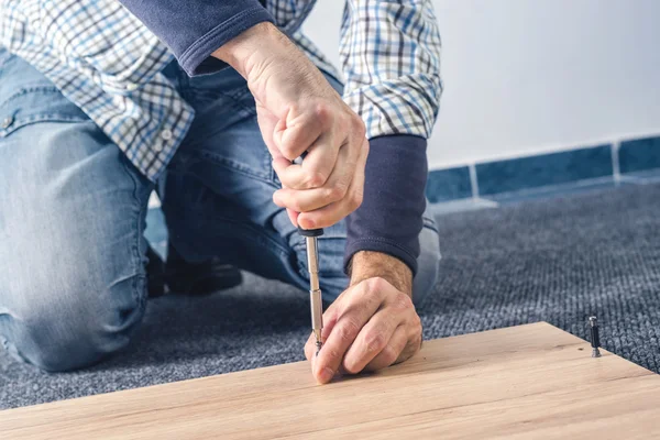 Uomo che monta mobili a casa, mano con cacciavite — Foto Stock