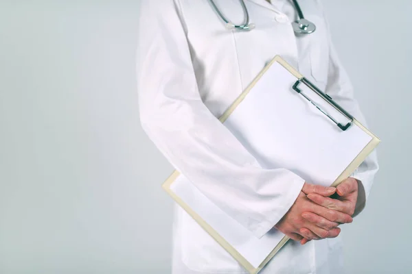 Femme médecin en uniforme blanc posant avec bloc-notes vierge — Photo
