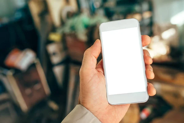 Mano masculina sosteniendo teléfono inteligente blanco con pantalla en blanco — Foto de Stock