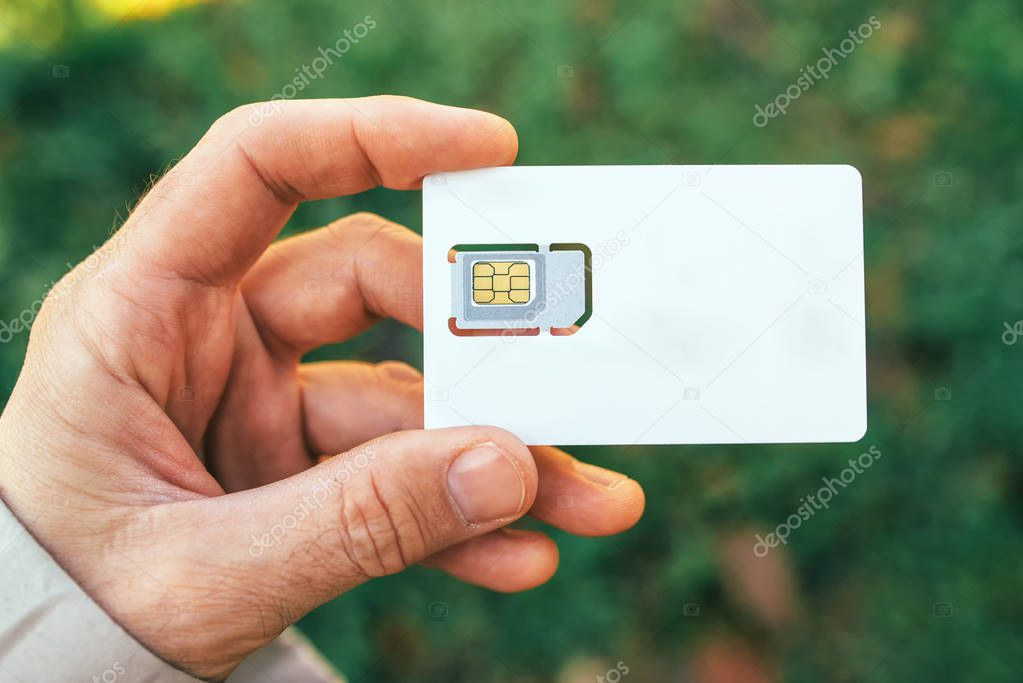 Male hand holding mobile phone SIM card