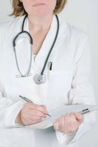 Kvinnliga läkare skriva på klippbordet anteckningar blankt papper — Stockfoto