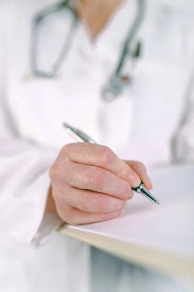Жінка-лікар в білій формі пише на кишені — стокове фото