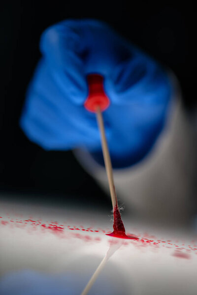 Forensic technician taking DNA sample from blood stain
