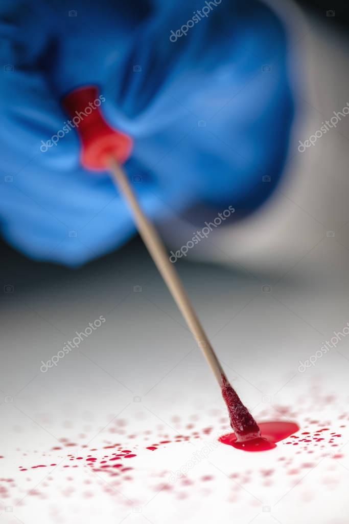 Forensic technician taking DNA sample from blood stain