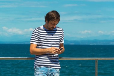 Deniz kenarında Sms gönderme soyulmuş denizci tişörtlü adam