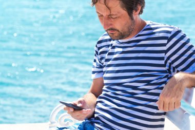 Cep telefonuyla deniz denizci çizgili tişörtlü adam