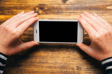 Yatay yatay yönlendirmeli olarak akıllı telefon kullanan kadın