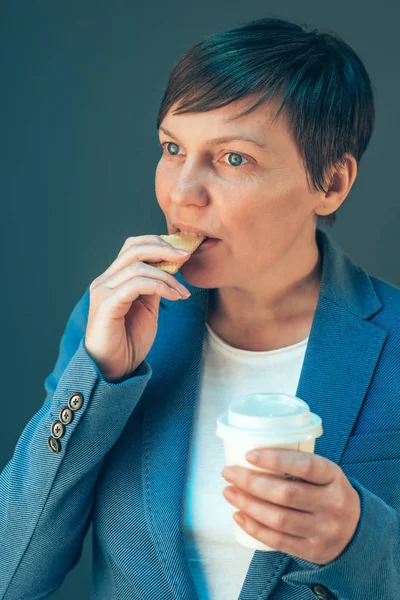 Businesswoman eating cookie on a break — Stock Photo, Image