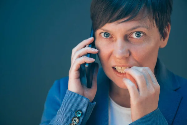 Nervózní podnikatelka kouše nehty během telefonních convers — Stock fotografie