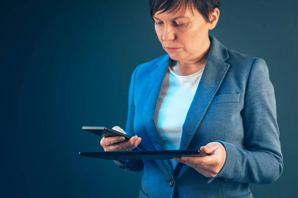 Businesswoman using mobile phone and tablet computer — Stock Photo, Image