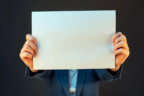 Mujer de negocios cubriendo la cara con papel en blanco como espacio de copia — Foto de Stock