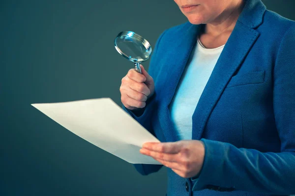 Женщина-налоговый инспектор смотрит на документ с увеличительным стеклом — стоковое фото