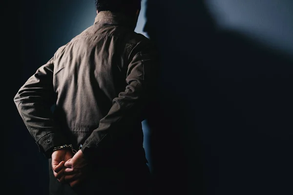 Arrested male criminal with handcuffs facing prison wall — Stock Photo, Image