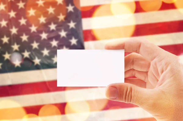 Hand mit leerer Visitenkarte und US-Flagge im Hintergrund — Stockfoto