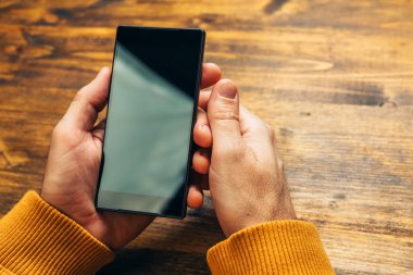 Siyah akıllı telefon boş ekrana bakarak işadamı