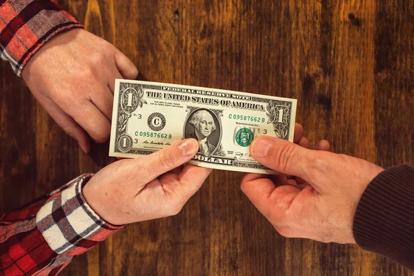 Mulher oferecendo uma nota de dólar para o homem — Fotografia de Stock